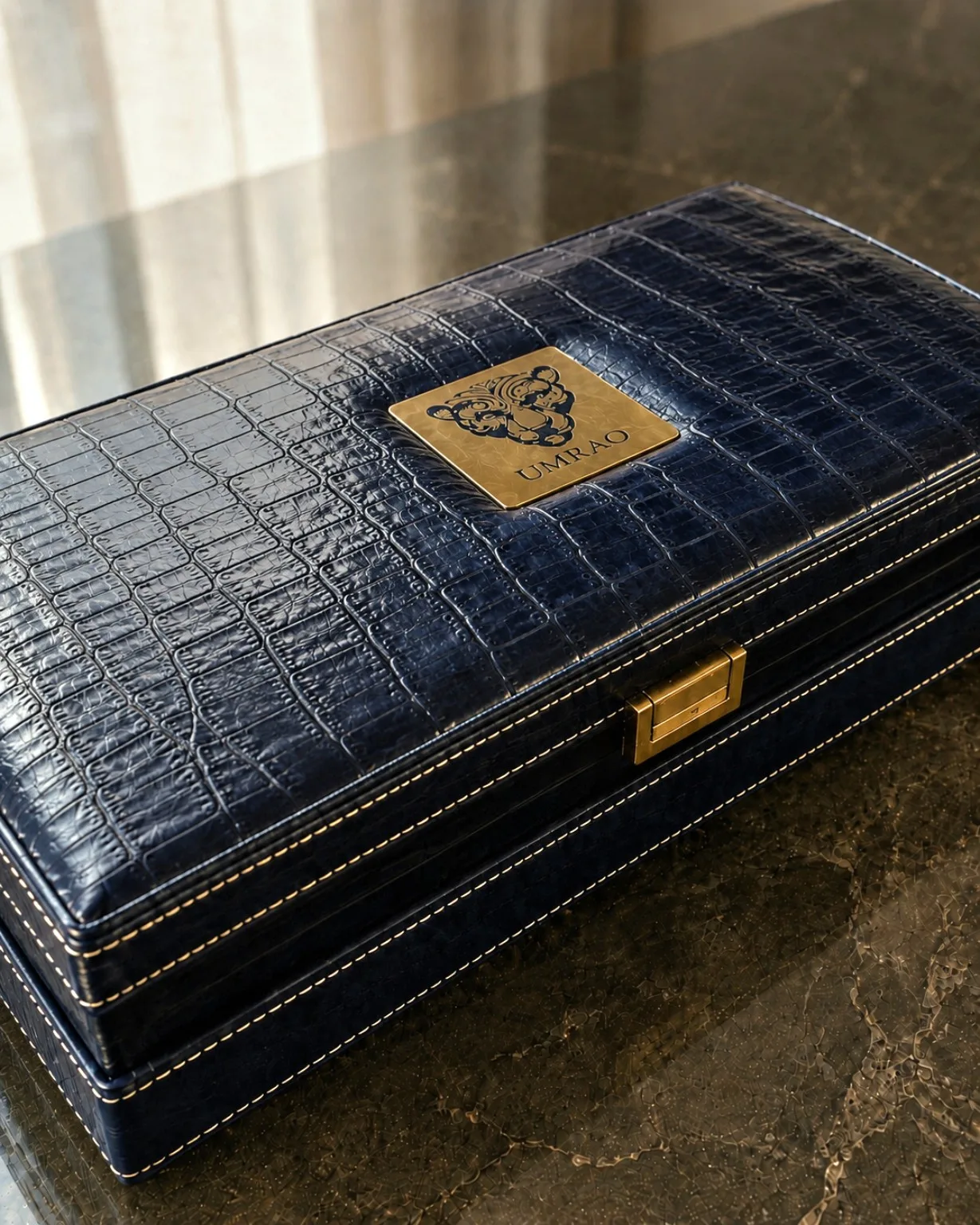 A closed navy coffret with the metal crest of the house
